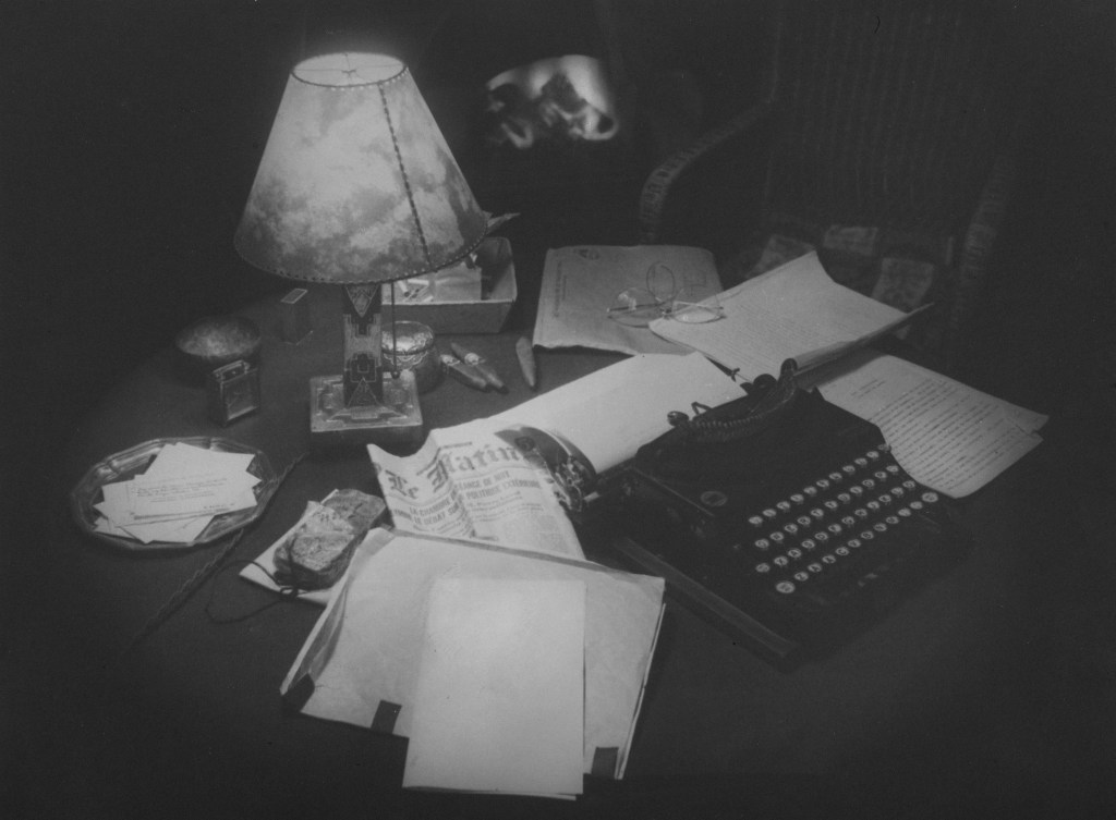 Typewriter on desk lamp pages strewn
